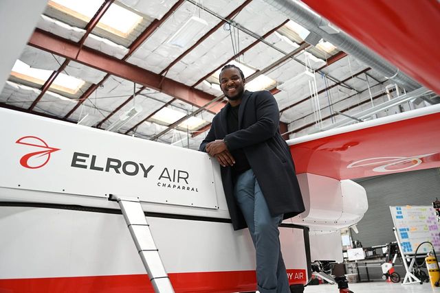 Elroy Air Director of Business Development Kofi Asante standing next to a prototype of Chaparral, Elroy Air's hybrid vertical takeoff and landing (VTOL) aircraft and cargo system.