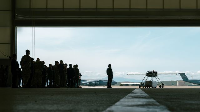 Shadow view of Ground Test Vehicle and onlooking crowd in Travis AFB hangar.