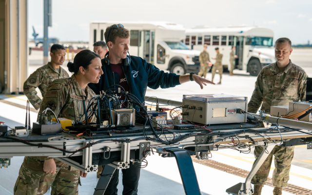 Ground Test Vehicle close-up with engineer and Air Force officers at Travis AFB.